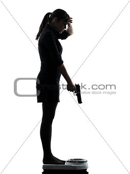woman standing on weight scale  despair aiming gun silhouette