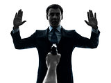 business man arms raised with gun pointing at him  silhouette