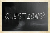 "questions" handwritten with white chalk on a blackboard