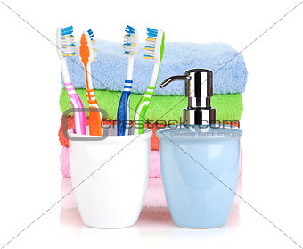 Four colorful toothbrushes, liquid soap and towels