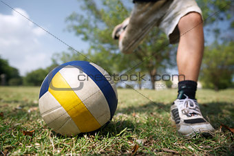 Kids playing soccer game, young boy hitting ball in park