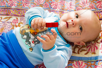 adorable baby with a toy in the hand on a colored blanket