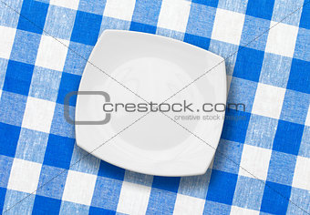white plate on blue checked fabric tablecloth