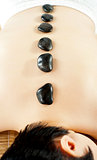 Naked woman getting spa hot stone treatment