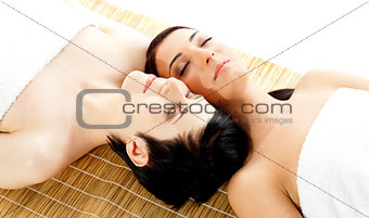 Two beautiful women friends relaxing on mat