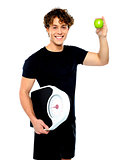 Fit guy with weighing scale and green apple