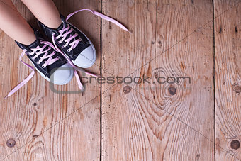 Child feet in sneekers on old wooden floor