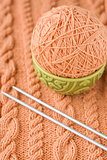 A peach-colored ball of yarn are in the national dish and needles for knitting