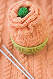 A ball of orange yarn to knit a flower on a orange background