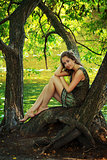 beautiful girl sitting on a large tree