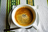A cup of coffee on the embroidered tablecloth