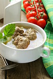 Soup with meatballs and vegetables in white bowl