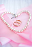 Two wedding rings on the pink background with pearl