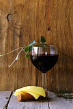 glass of red wine and slices of cheese on a wooden table