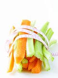 carrots, green celery,  measuring tape on a white background