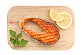 Grilled salmon with lemon slices and parsley on cutting board
