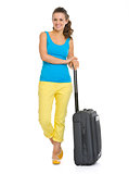Full length portrait of smiling young tourist woman with wheel b