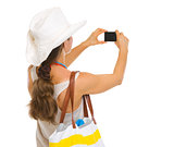 Beach woman taking photo with camera . rear view