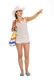 Full length portrait of happy beach young woman pointing on copy