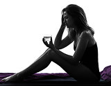  woman headache sitting in bed taking medicine silhouette