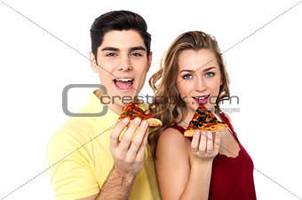 Couple posing with pizza slice, about to eat