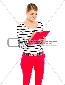 Young girl writing makes notes on clipboard