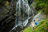 Young man with a dog near a waterfall