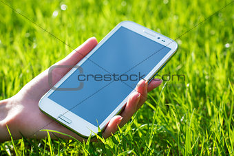 Woman Hand Holding Smart Phone on Green Background