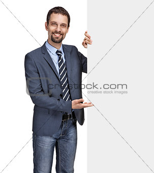 Happy smiling young businessman showing large blank grey signboard