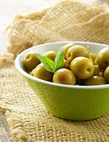 green  marinated olives with herbs  on a wooden table