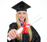 Smiling young woman in graduation gown showing diploma