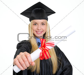 Smiling young woman in graduation gown showing diploma