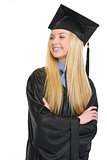 Happy young woman in graduation gown looking on copy space