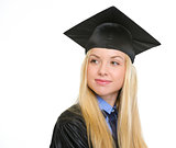 Happy young woman in graduation gown looking on copy space