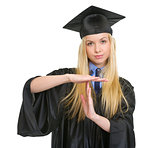 Young woman in graduation gown showing stop gesture