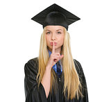Young woman in graduation gown showing shh gesture