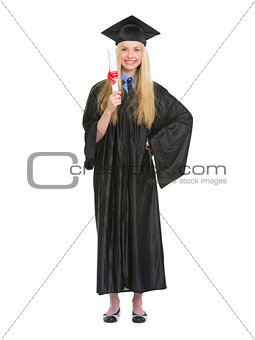 Full length portrait of young woman in graduation gown showing d