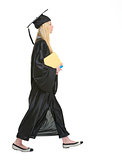 Young woman in graduation gown with books going sideways
