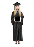 Full length portrait of young woman in graduation gown showing t