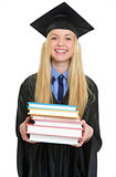 Happy young woman in graduation gown giving books