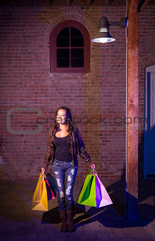Mixed Race Young Woman Walking Carrying Shopping Bags at Night
