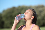 Woman drinking water from a plastic bottle in the mountain