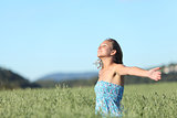 Beautiful woman breathing happy with raised arms in a green oat meadow