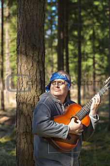 Man playing guitar in forest
