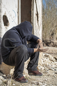 Homeless person begging near the destroyed house