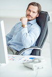 Handsome businessman sitting in chair in front of computer