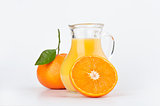 Orange juice in pitcher and oranges
