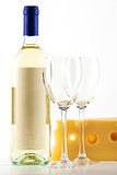 Bottle of white wine and two empty wine glasses and cheese