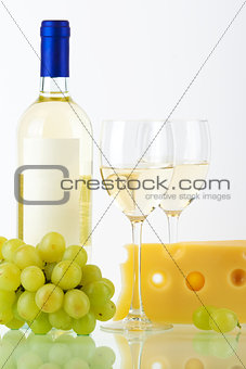 Bottle of white wine, wine glasses, cheese and grape