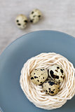 Three quail eggs in the nest with the thread on the plate